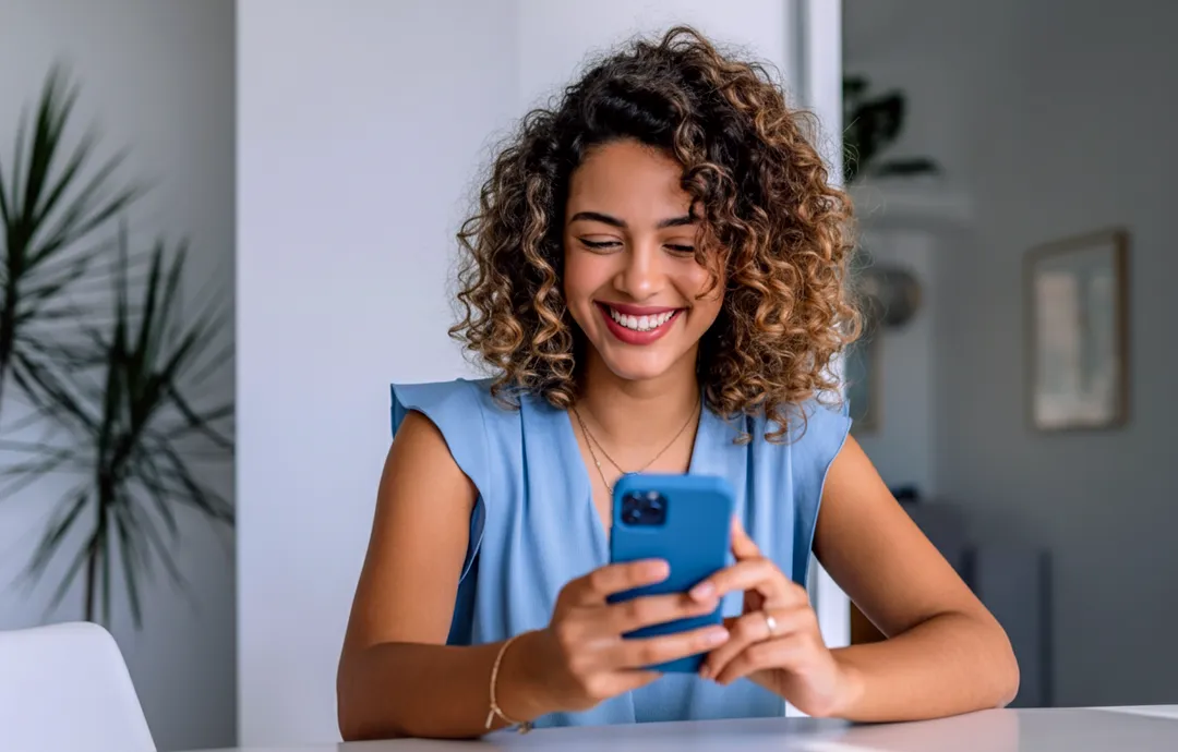 Mulher sorrindo enquanto usa o smartphone